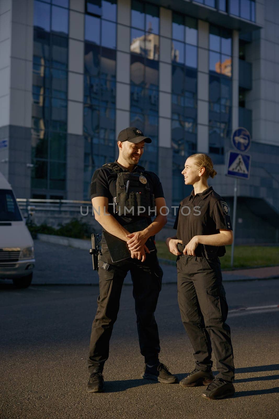 Nice conversation of to friendly smiling patrol officers standing at police station department outdoors