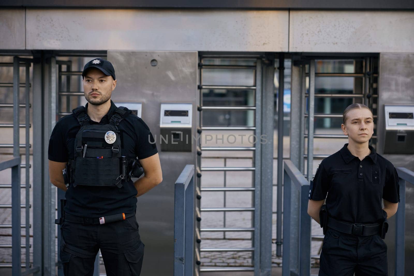 Diverse armed police officers wearing protective bulletproof vest patrolling and guarding entrance to public subway