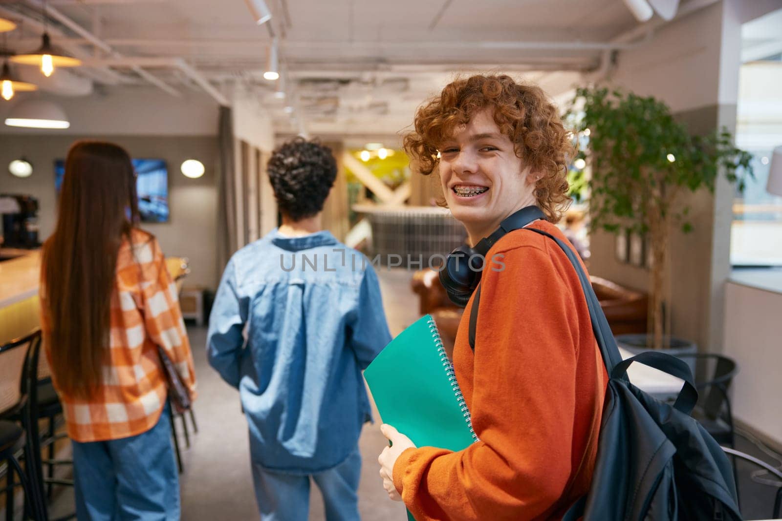 Cheerful teenager working in office together. Guys helping each other with tasks