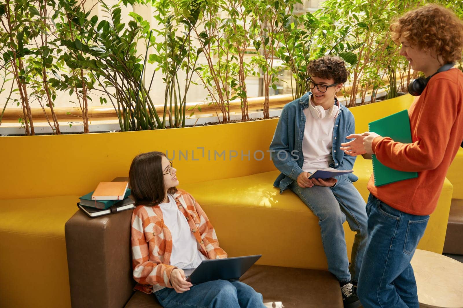 Group of teenagers in coworking office. Three young employees discussing new work project