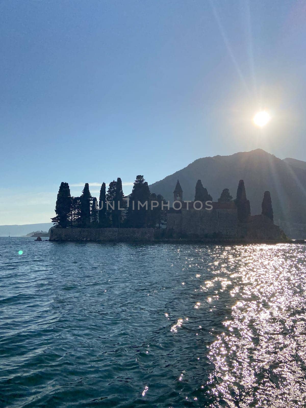 Coastal village nestled between majestic mountains and a serene sea under a clear blue sky. Scene captures the allure of tranquil coastal living and breathtaking natural scenery