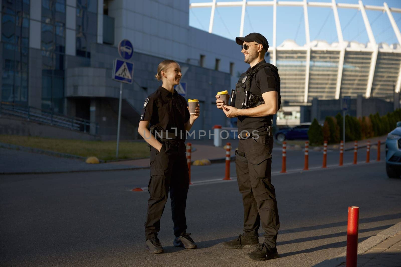 Cheerful patrol officers talking together drinking coffee having work day break. Nice conversation and friendly relationship at job