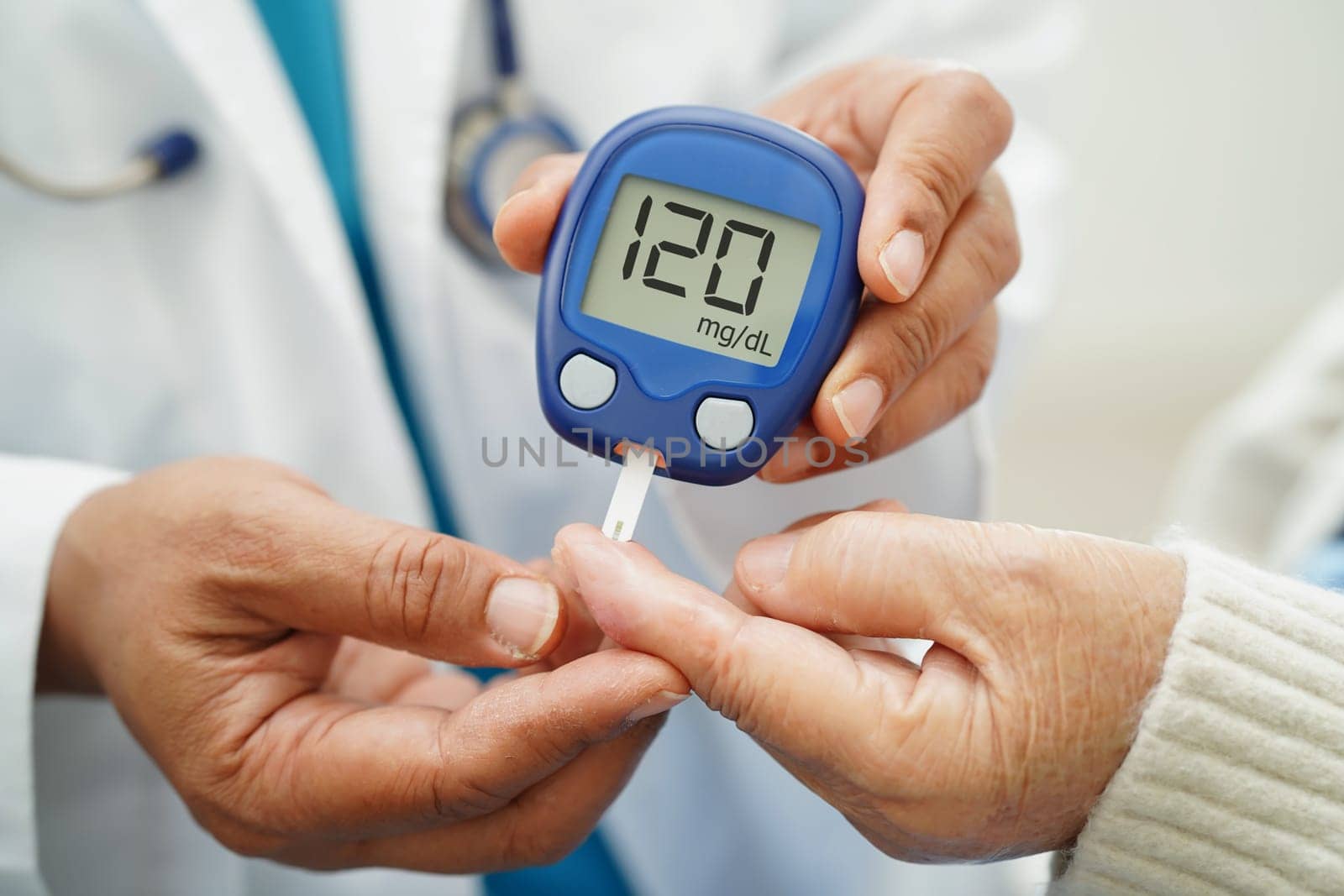 Asian doctor using digital glucose meter for check sample blood sugar level to treatment diabetes.