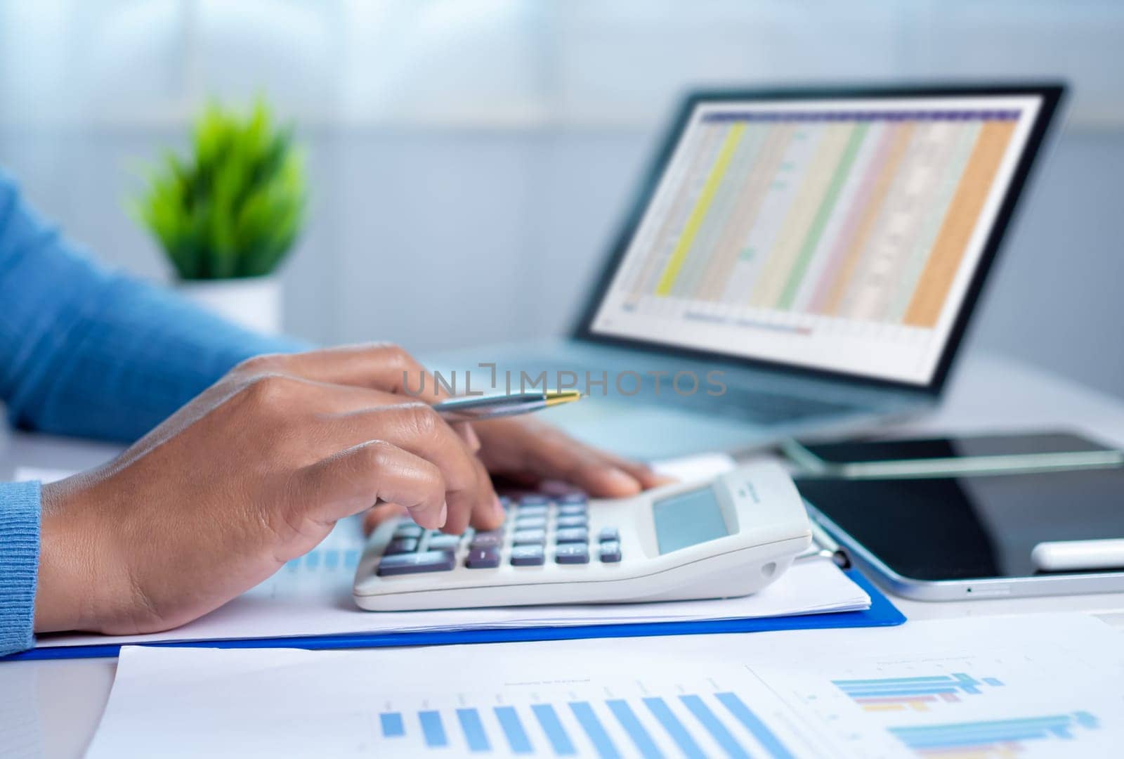 Businesswoman hand working with finances about cost and calculator and laptop with tablet on desk at office in morning light, Business accounting concept, Calculating or checking balance.