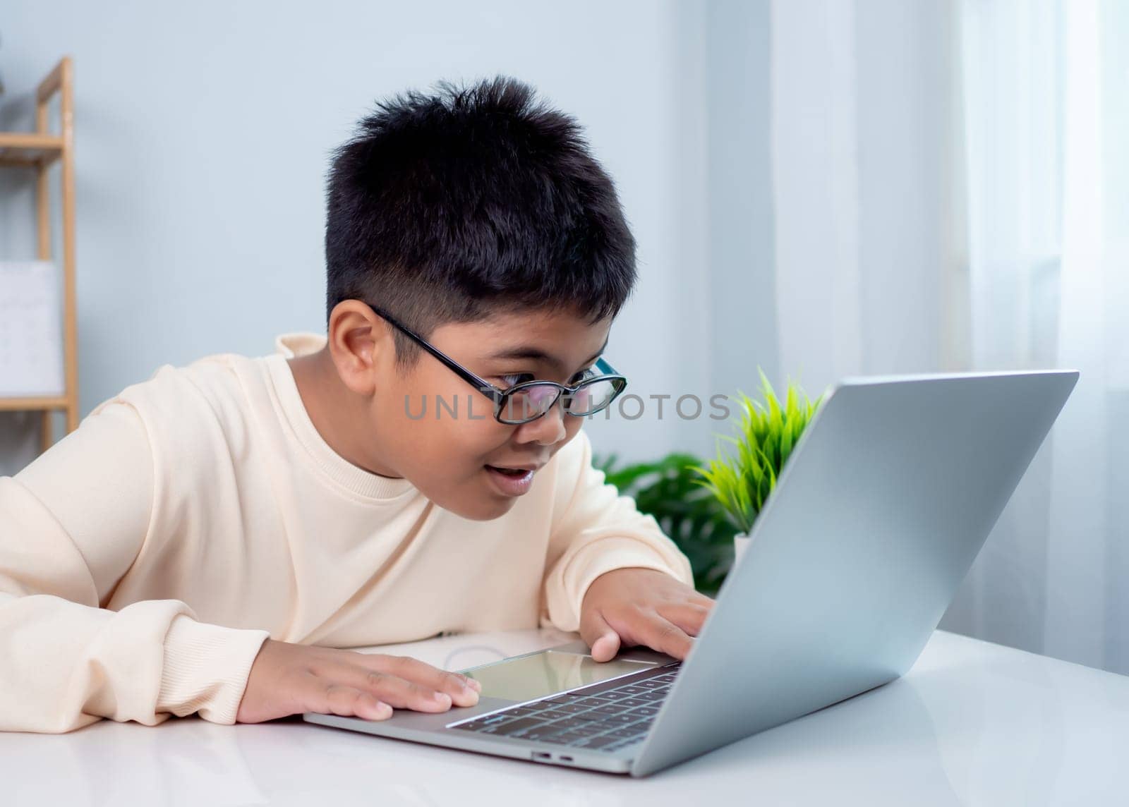 Educational of tech concept, Staying at home, Little Asian boy student using computer laptop learning.  Presenting a modern educational way of life. Virtual internet online class from school teacher.