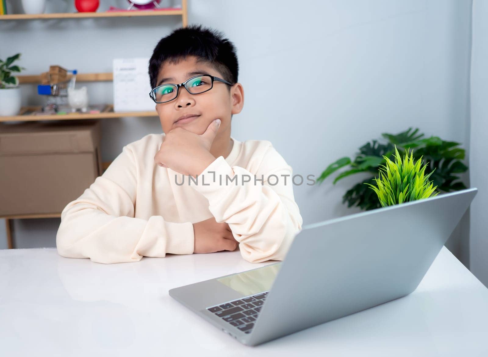 Asian student boy thinking using computer learning. Educational of tech concept, Staying at home, Presenting a modern educational way of life. Virtual internet online class from school teacher.