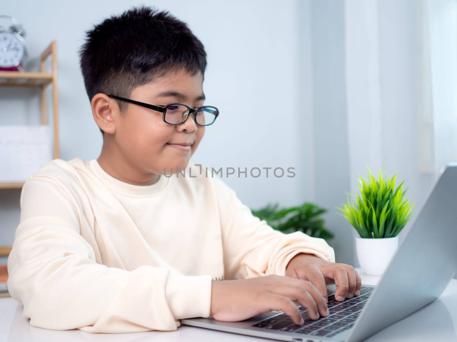 Educational of tech concept, Staying at home, Little Asian boy student using computer laptop learning.  Presenting a modern educational way of life. Virtual internet online class from school teacher.