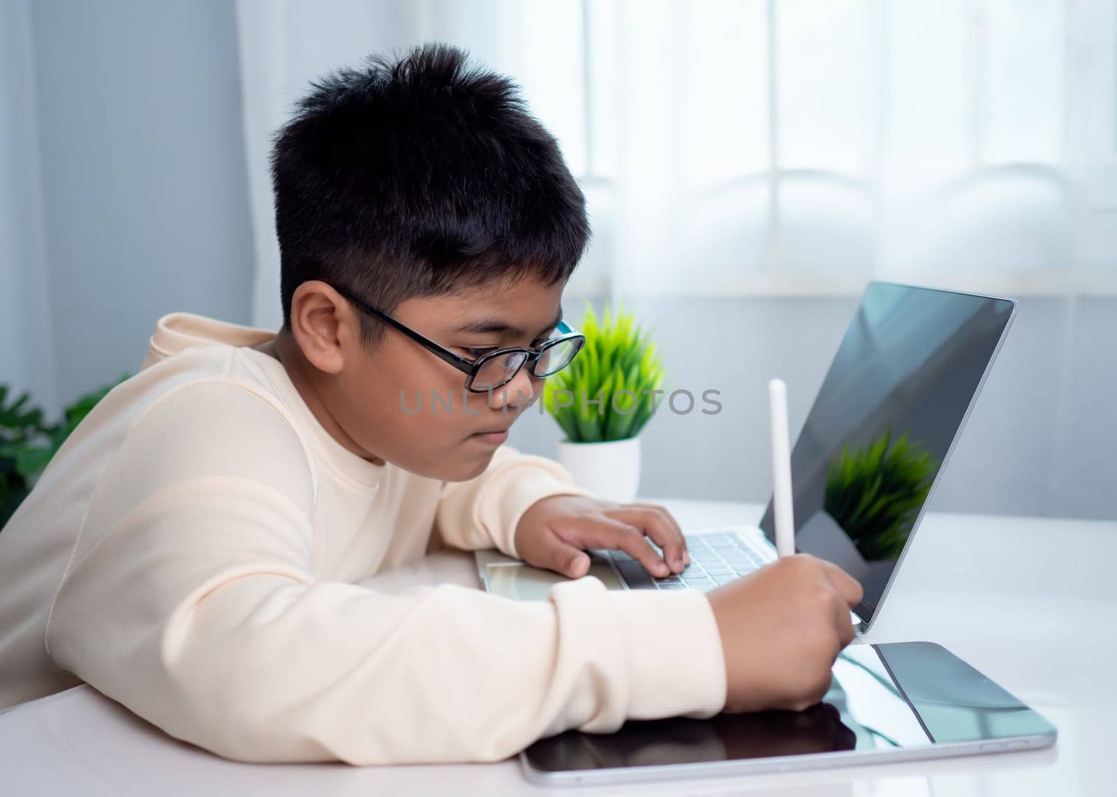 Asian student boy using computer and tablet learning. Educational of tech concept, Staying at home, Presenting a modern educational way of life. Virtual internet online class from school teacher.
