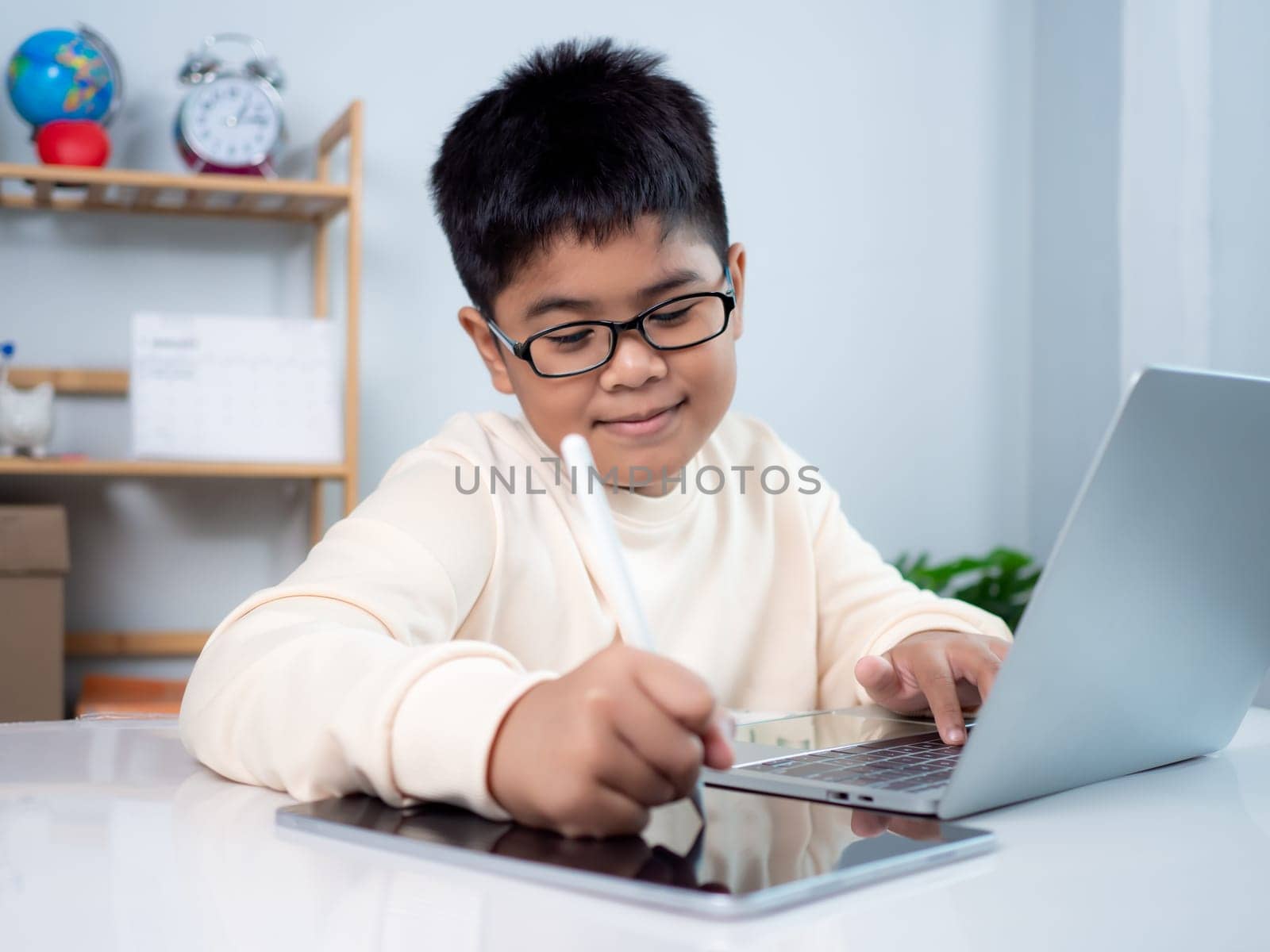 Asian student boy using computer and tablet learning. Educational of tech concept, Staying at home, Presenting a modern educational way of life. Virtual internet online class from school teacher.