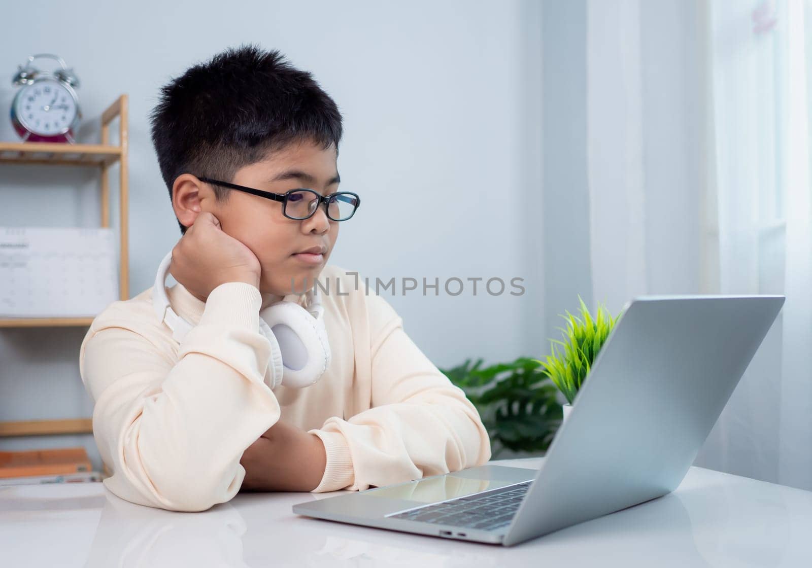 Educational of tech concept, Staying at home, Little Asian boy student using computer laptop learning.  Presenting a modern educational way of life. Virtual internet online class from school teacher.