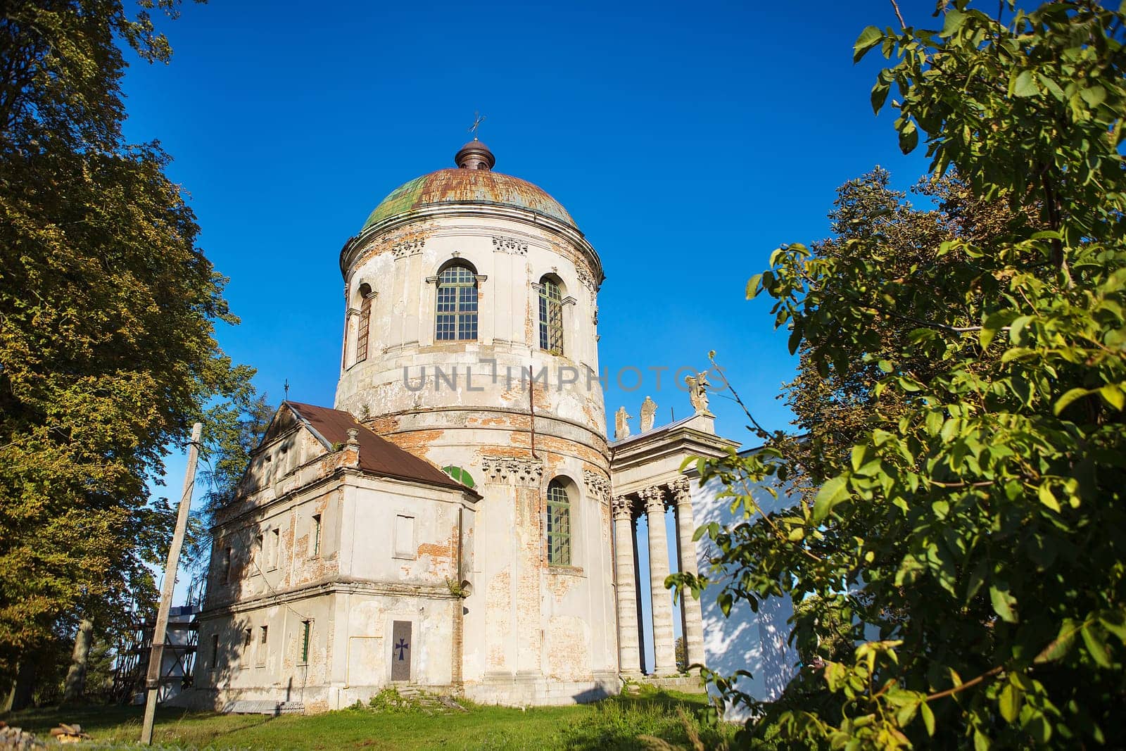 Old church of Exaltation 18th century near Pidhirtsi Castle between trees, Ukraine.