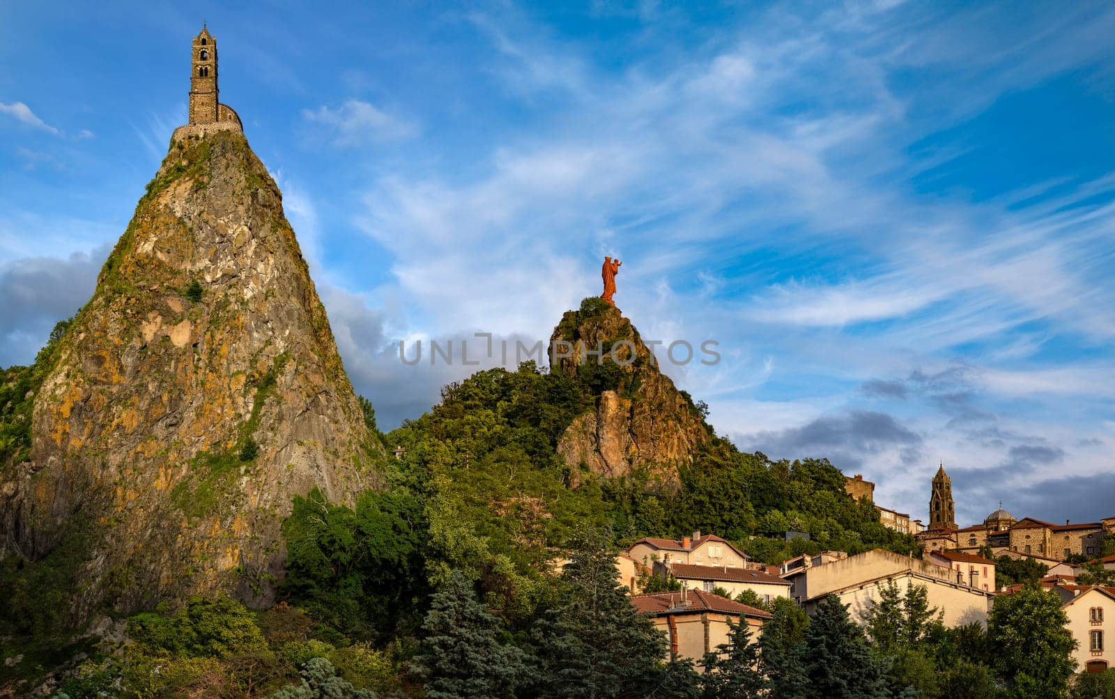 Chapel of St Michel-dAiguilhe and Statue of Notre-Dame de France above the bell tower of Cathedral Nore-Dame in the city of Le Puy-en-Velay in the Auvergne-Rhone-Alpes region of south-central France.