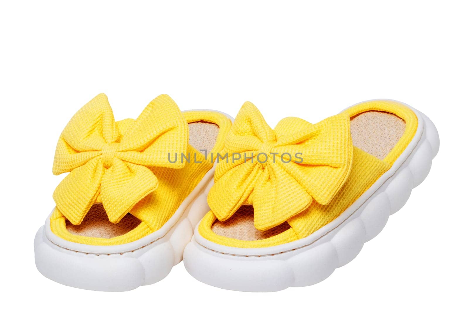 Slippers isolated. Close-up of a pair female yellow soft cosy house slipper with a large bow isolated on a white background, Clipping path. Macro. Womans shoes.