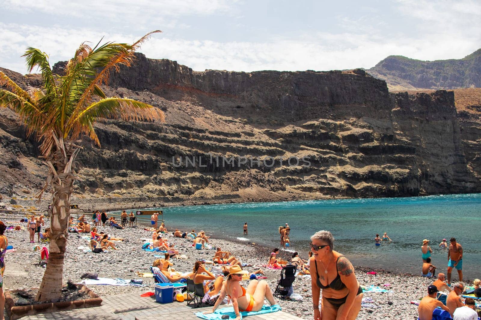 Puerto de las Nieves, Gran Canaria Island, Spain - 20 July 2024. Tourists on the stony beach Playa de las Nieves with a view on the rocks.