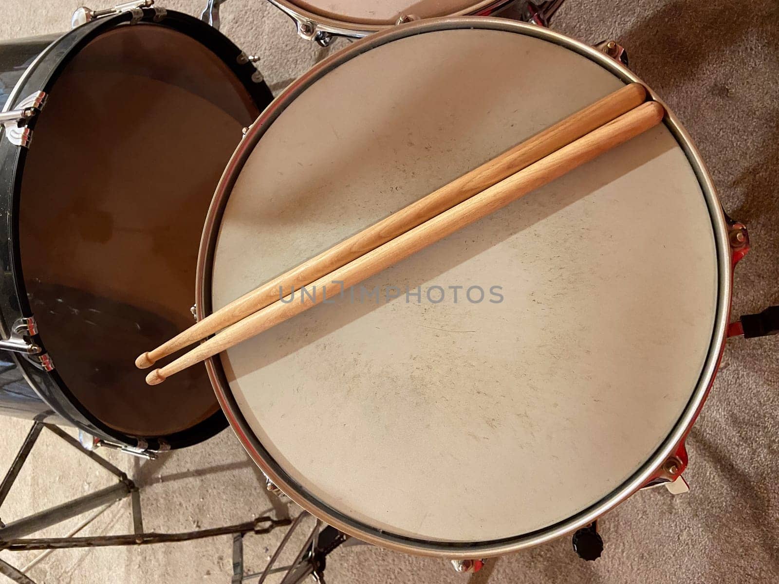 Pair of wooden drumsticks rests on a snare drum, inviting rhythm and energy. Musical experience waiting to unfold in this intimate setting.