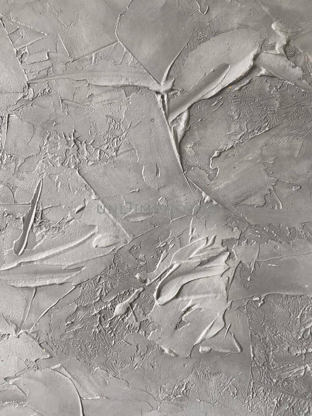 Textured gray canvas leans against a white brick wall, offering a stark contrast and highlighting the intricate details within the artwork. Artistic blend of the canvas meets the structured simplicity of the urban backdrop.