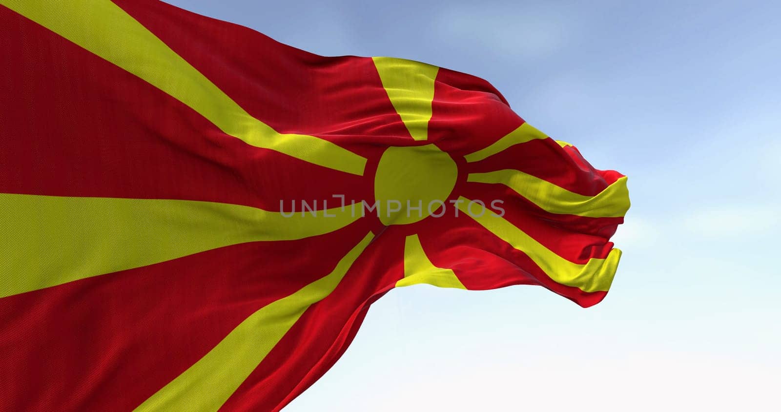 North Macedonia national flag waving in the wind on a clear day. Stylized yellow sun with eight rays extending to the edges of a red field. 3d illustration render. Fluttering fabric.