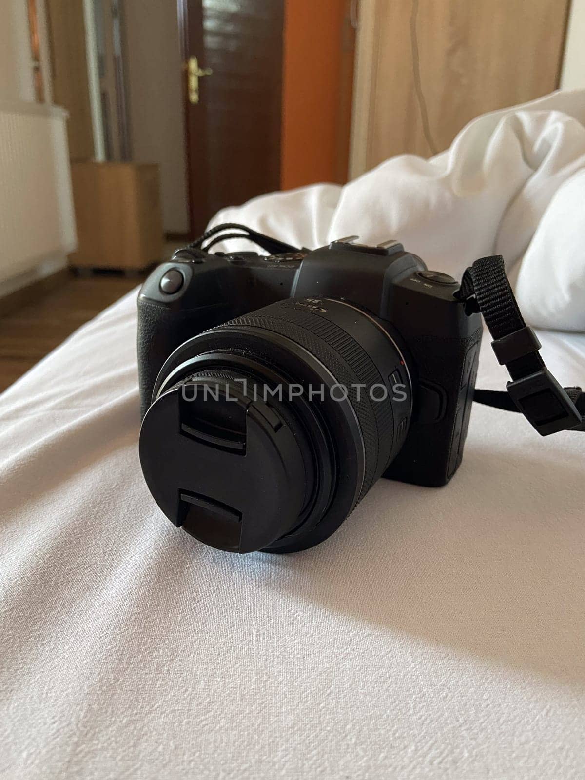 Digital camera rests on a white bed, ready for use, symbolizing creativity and exploration. Relaxed setting suggests a moment of pause before capturing new memories and experiences.