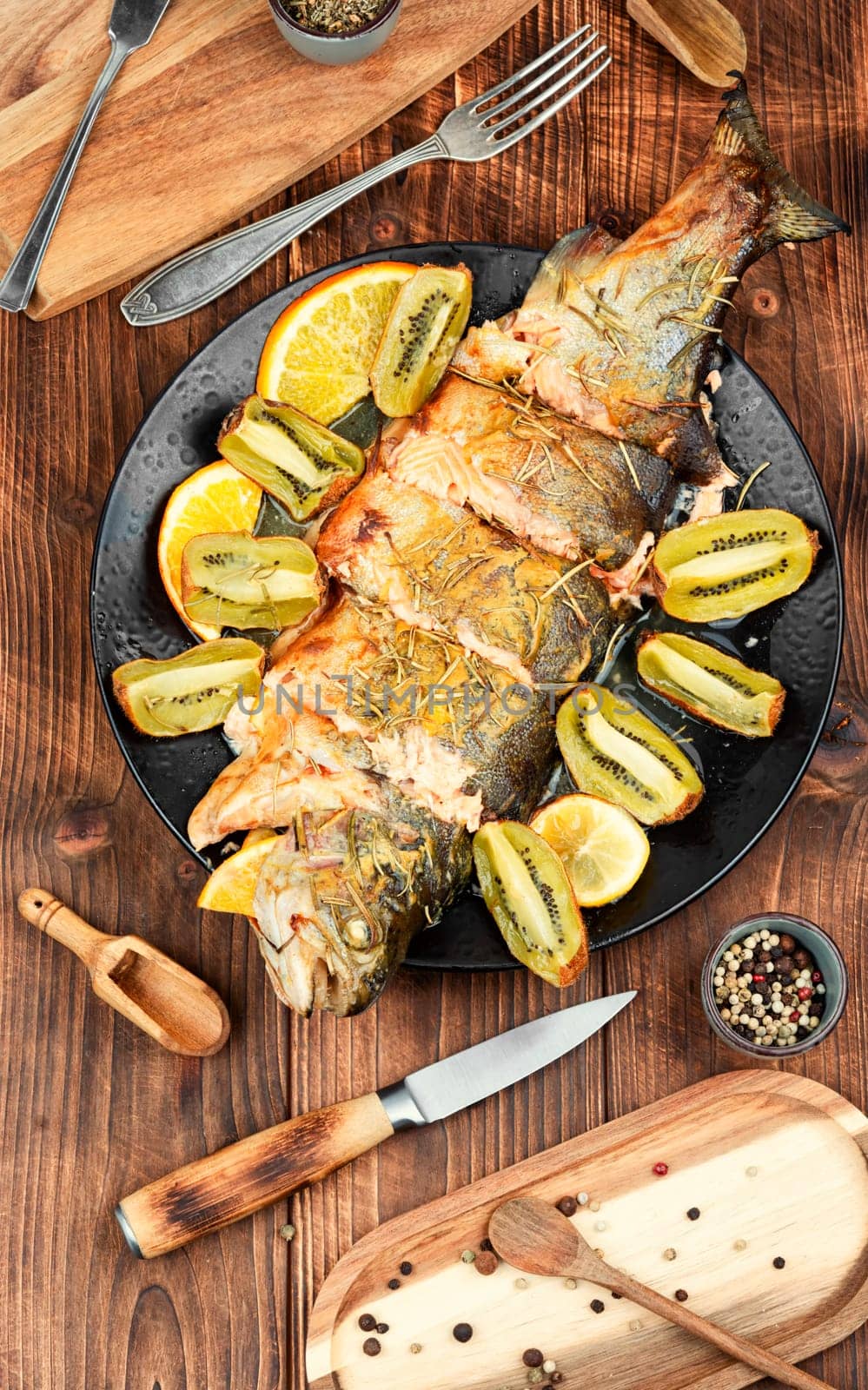 Whole trout fish baked in an oven with kiwi. Space for text.