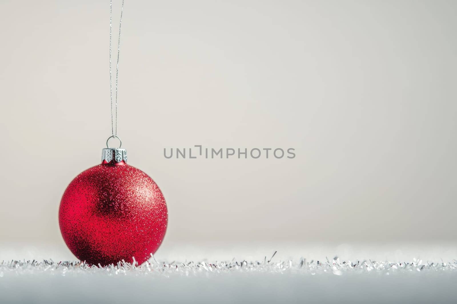 A vibrant red ornament hangs delicately catching light against a soft neutral background creating a festive holiday ambiance.