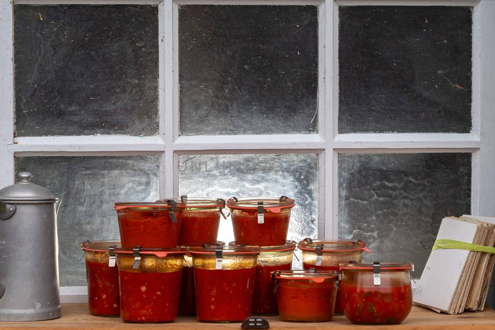 A row of jars filled with red sauce sit on a counter next to a coffee pot. Concept of warmth and comfort