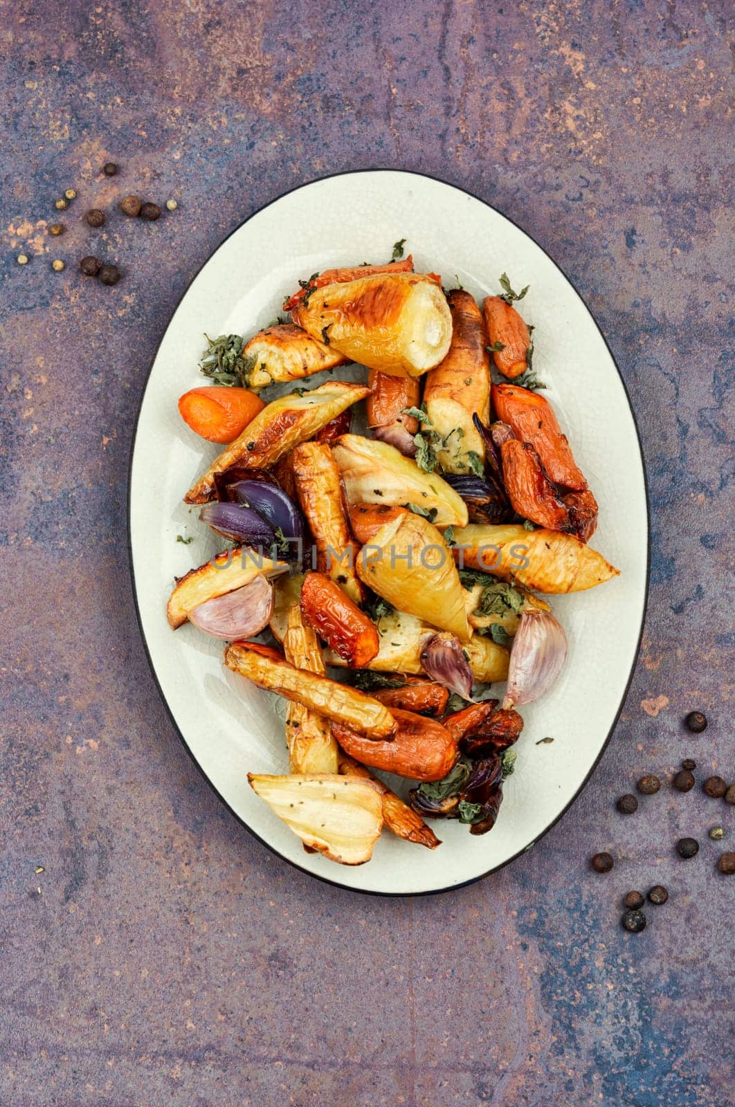 Roasted root vegetables, baked parsnip root, red onions, carrots, and garlic for a vegan dish.