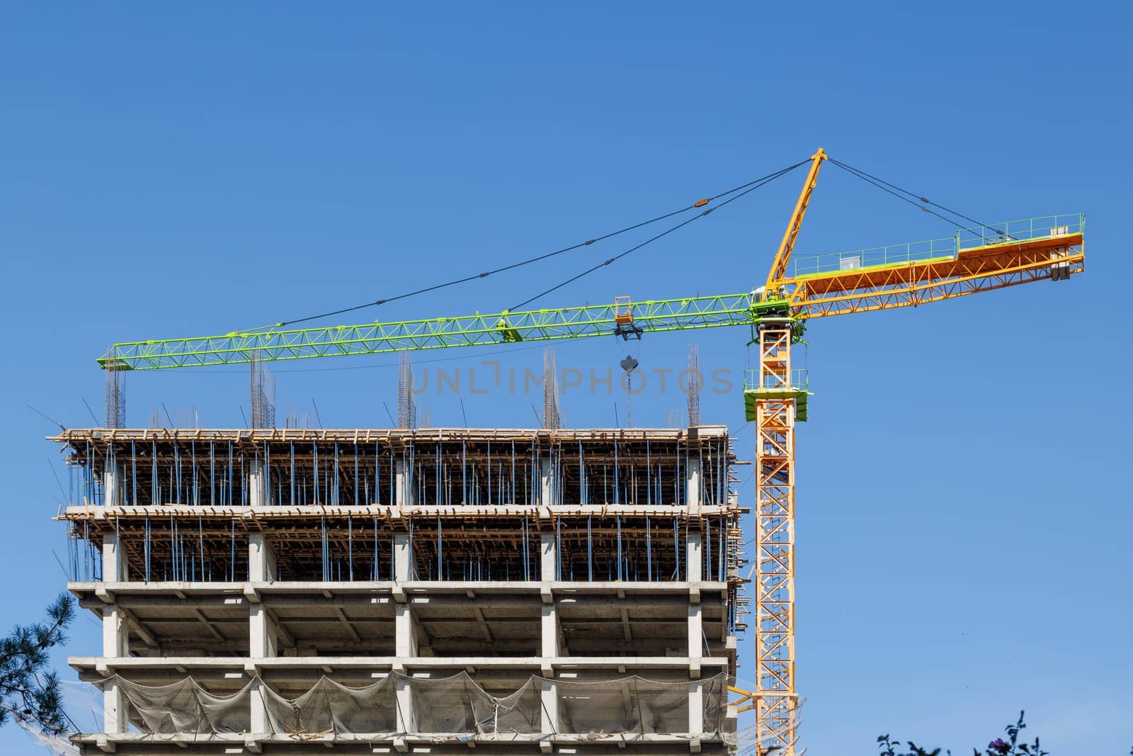 A contemporary construction site showcasing a large tower crane and the building framework set against a clear blue sky