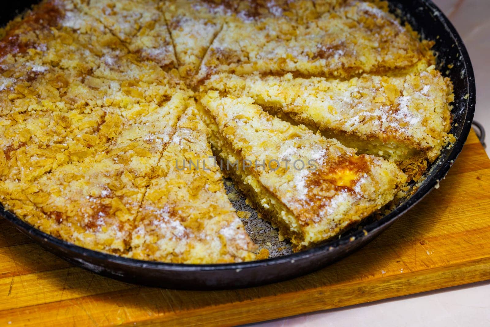 domestic apple pie in a black round cast iron pan sliced into sectors, closeup