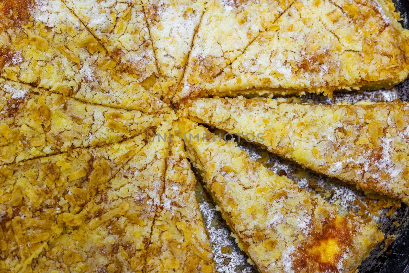 domestic apple pie in a black round cast iron pan sliced into sectors, closeup