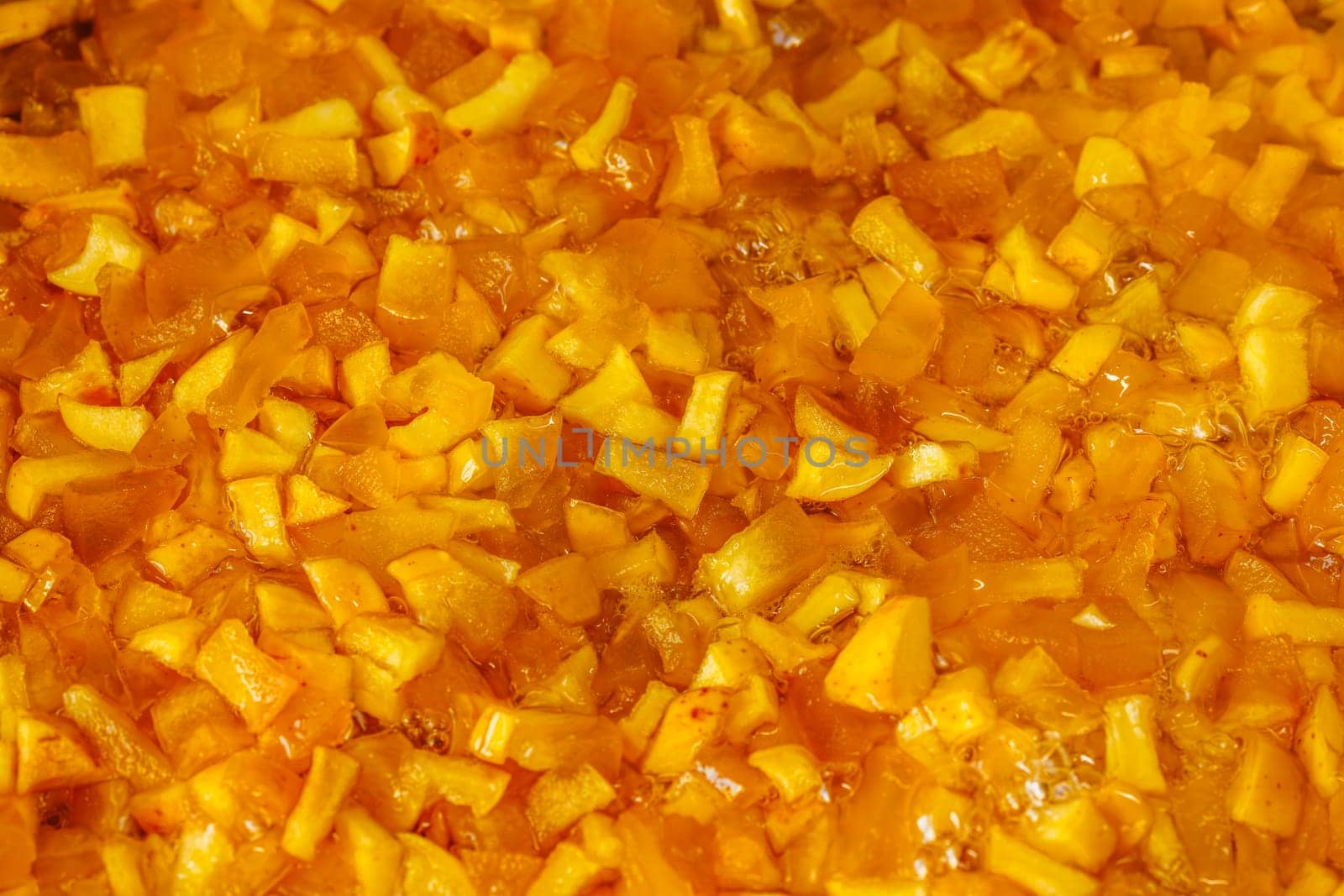 full-frame background and texture of sliced yellow apples soaking in syrup during confiture cooking.