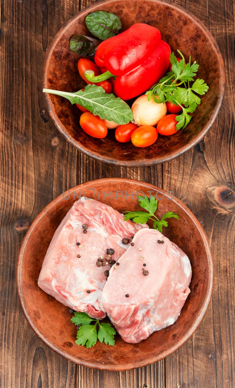 Raw pork loin chops for grill, barbecue or cooking with spices and vegetables on wooden background. Rustic style.