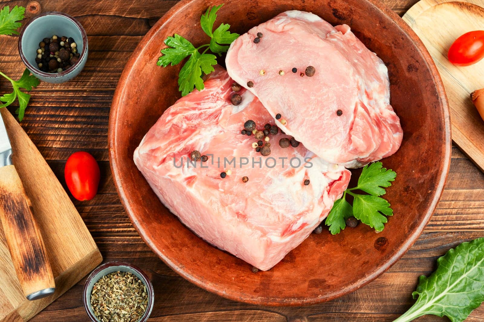 Raw pork loin chops for grill, barbecue or cooking with spices and vegetables on wooden background. Rustic style.