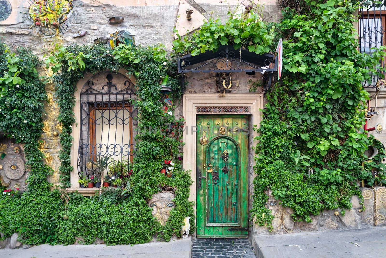 A striking green door framed by lush greenery and ornate windows enhances the historic beauty of Icherisheher, Baku. The natural elements add life to the traditional architecture