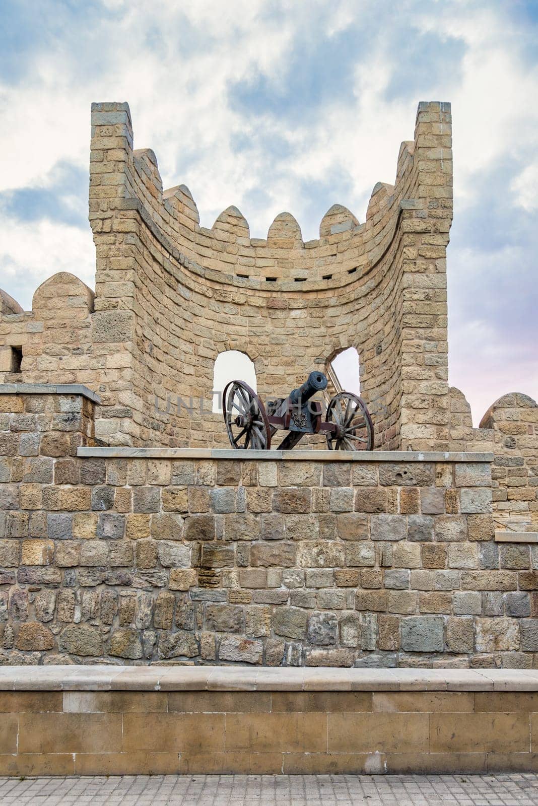 Historical fortification in the old city of Baku, Azerbaijan, Icherisheher, showcases a section of the city's ancient stone walls, featuring a cannon, mounted on wheels, rests atop the wall