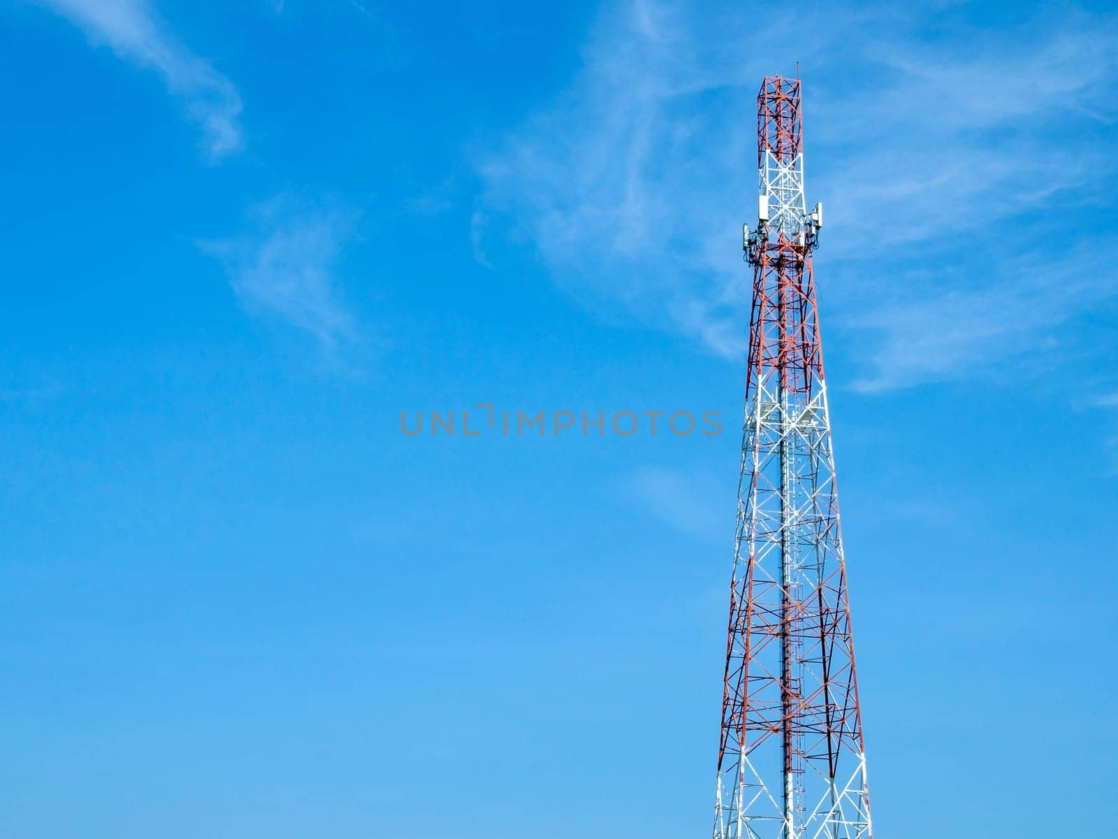 A telecommunications tower with various forms of antennas installed on its body, High antenna tower pillar of cellular communication on the blue sky background.