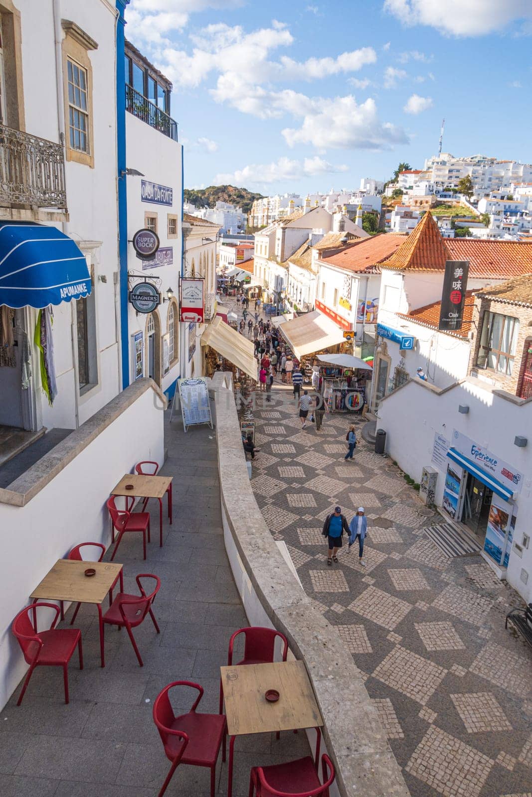 Albufeira, Portugal - April 27, 2024: traditional buildings and tourists photographed in a street of  Albufeira at the Algarve coast of Portugal