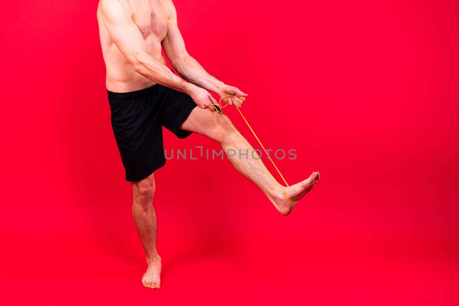 Fit man jumping with skipping rope. Isolated on a red studio background