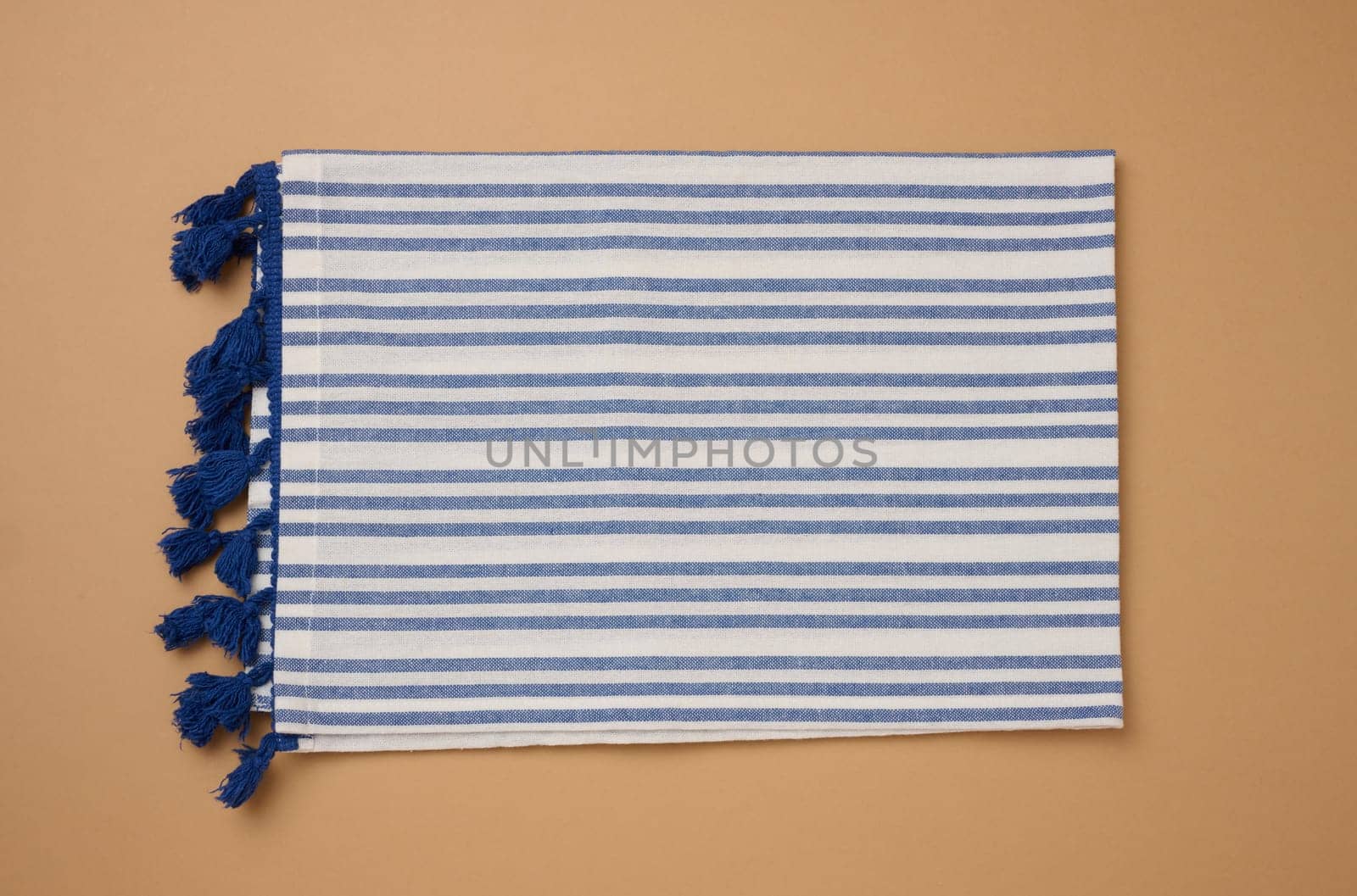 Folded linen striped kitchen towel on brown background, top view