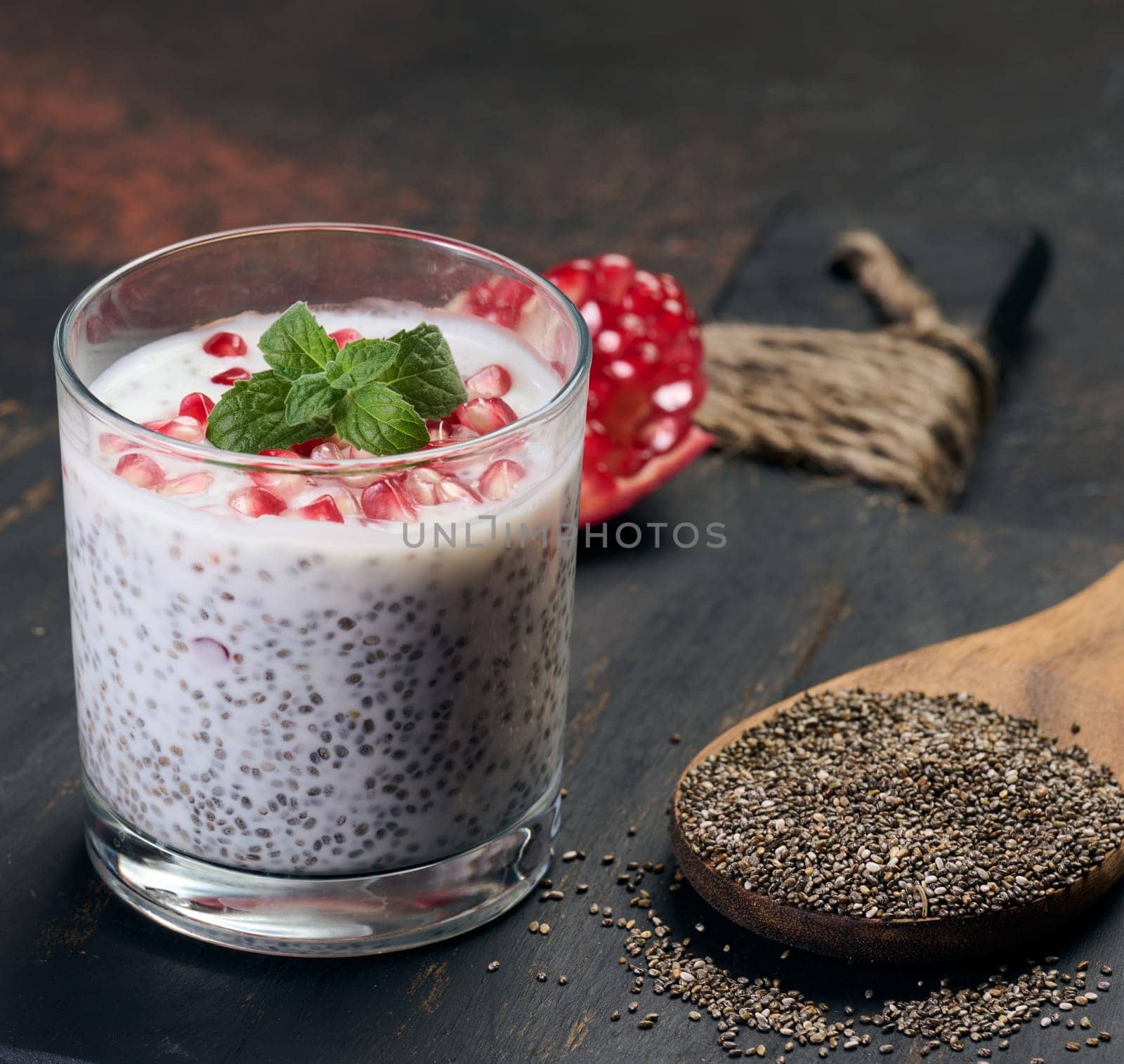 Glass of chia seeds and yogurt with pomegranate on table