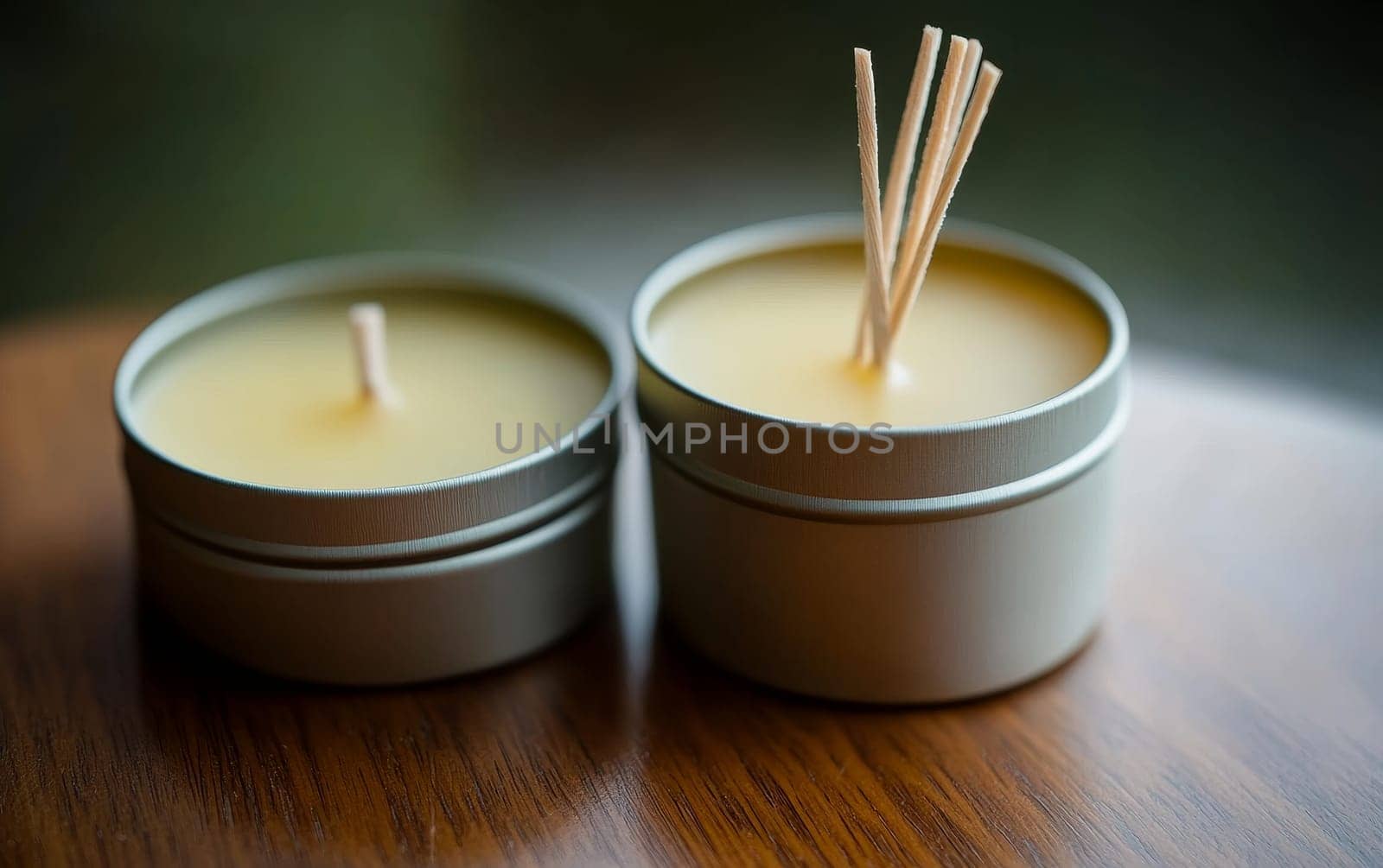 Two metal tin soy wax candles with wooden wicks on wooden surface. Natural aromatherapy and eco friendly home decor concept with soft focus background.