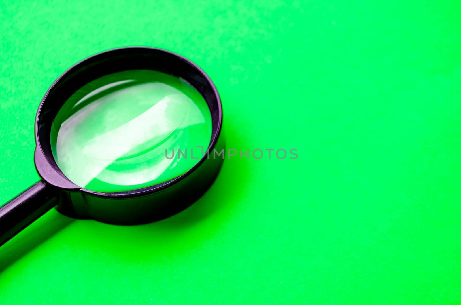 Magnifying glass on green cover background with customizable space for text or ideas.