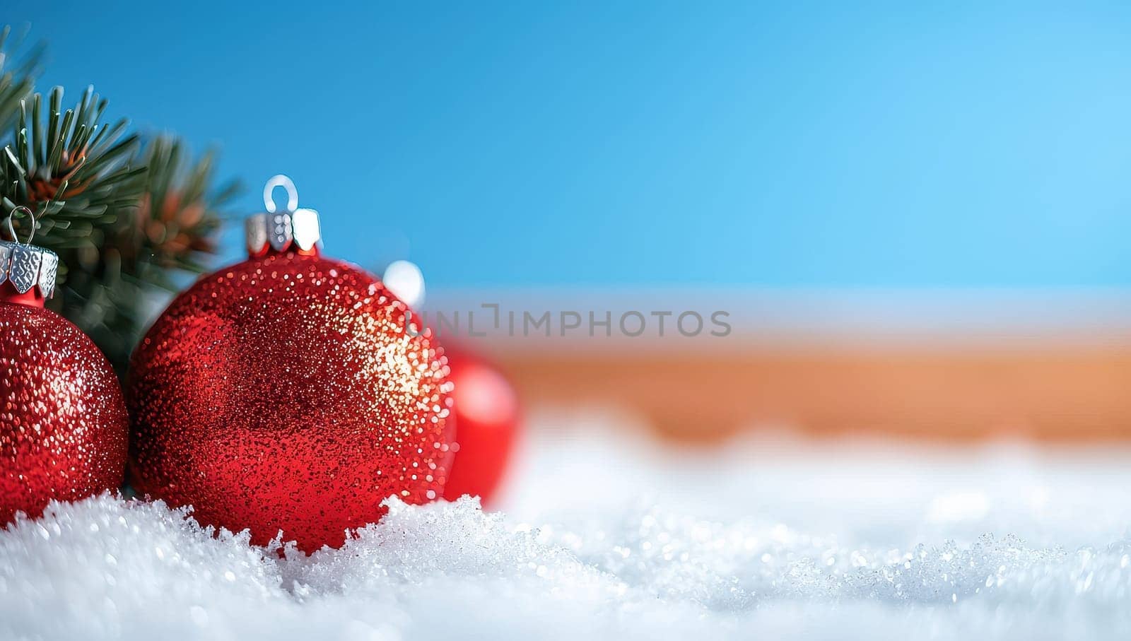 Red Christmas baubles nestled in snow with a fir tree branch. Festive holiday background with copy space.