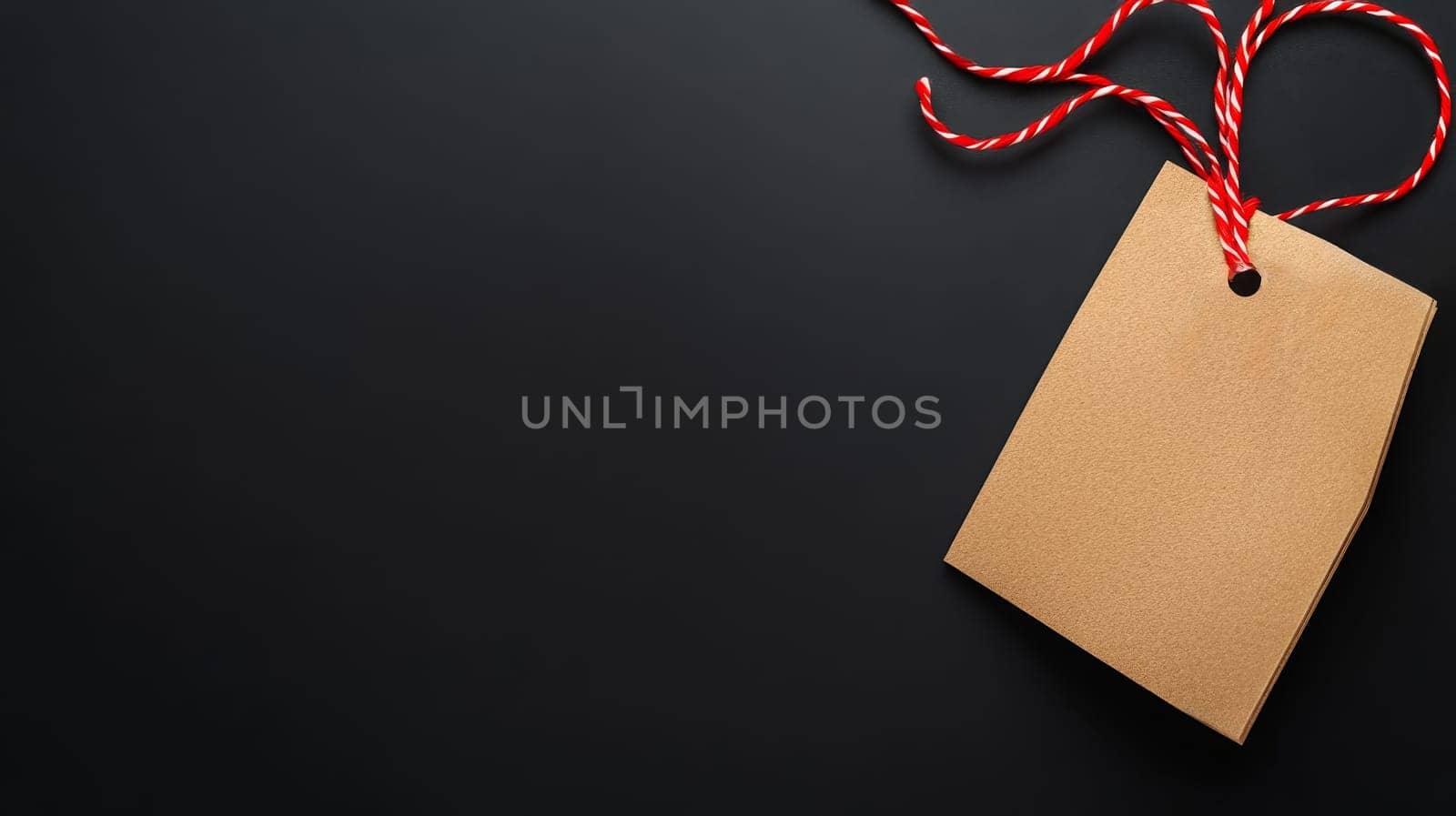 Simple kraft paper tag with red string on a dark surface, perfect for labels and messages with copy space. Black Friday sale concept with empty place for text.
