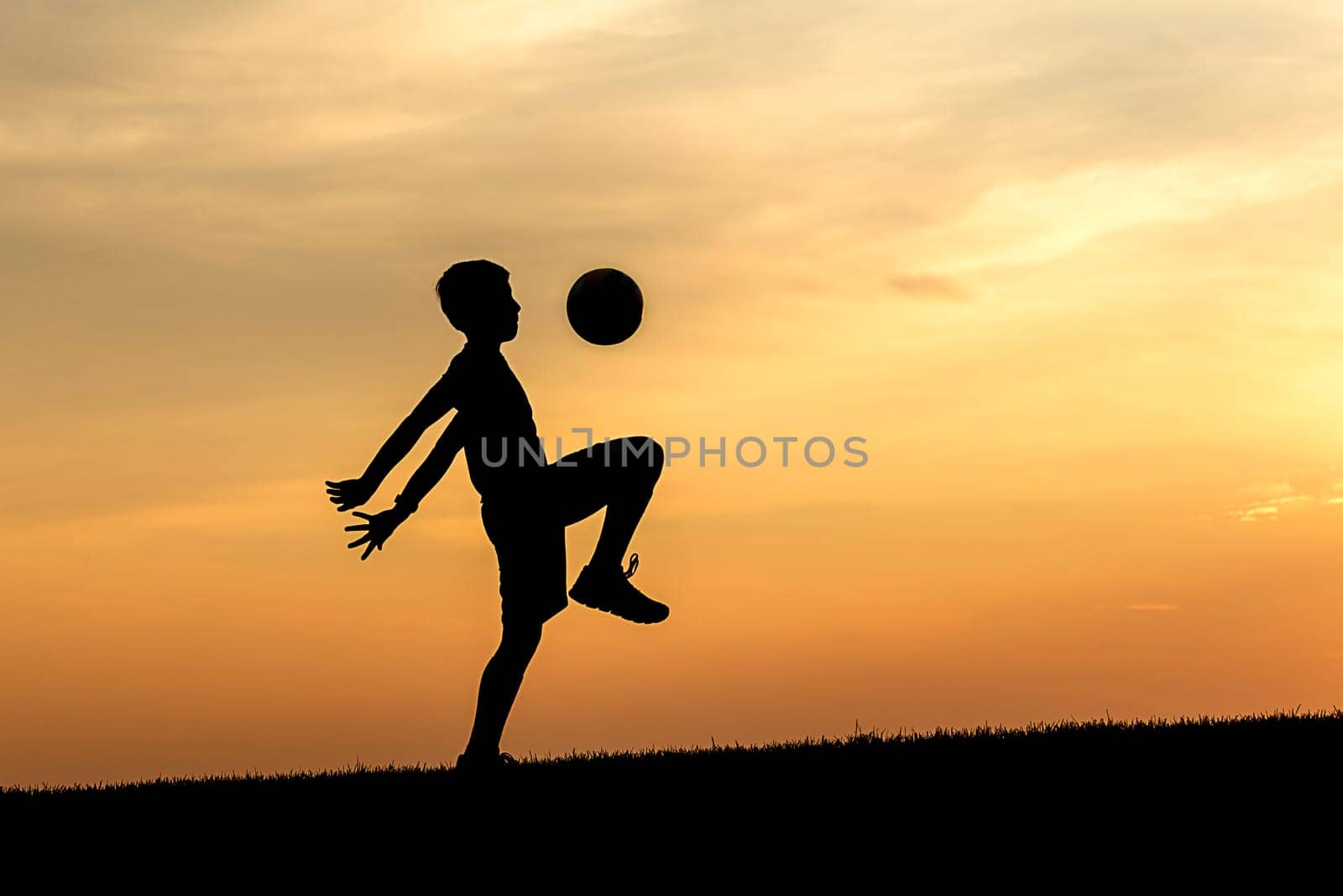 A concept photo of a young athlete practicing soccer at sunset.