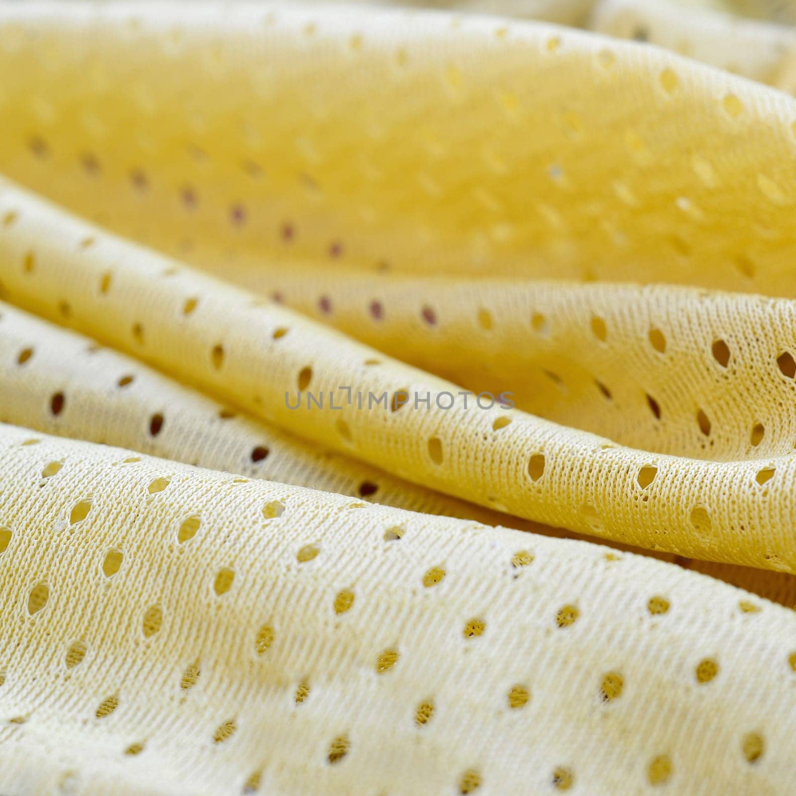Yellow mesh sport wear fabric textile pattern background. Yellow color football jersey clothing fabric texture sports wear. Breathable porous poriferous material air ventilation with small holes