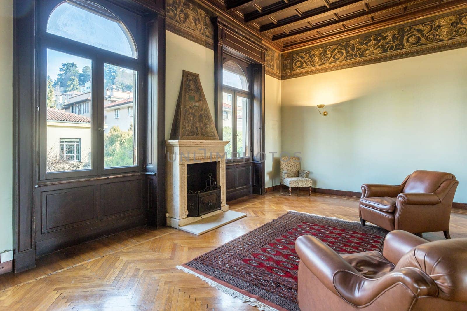 Interior of an ancient luxury house. Decorated wooden ceiling. Elegant fireplace. Living room.