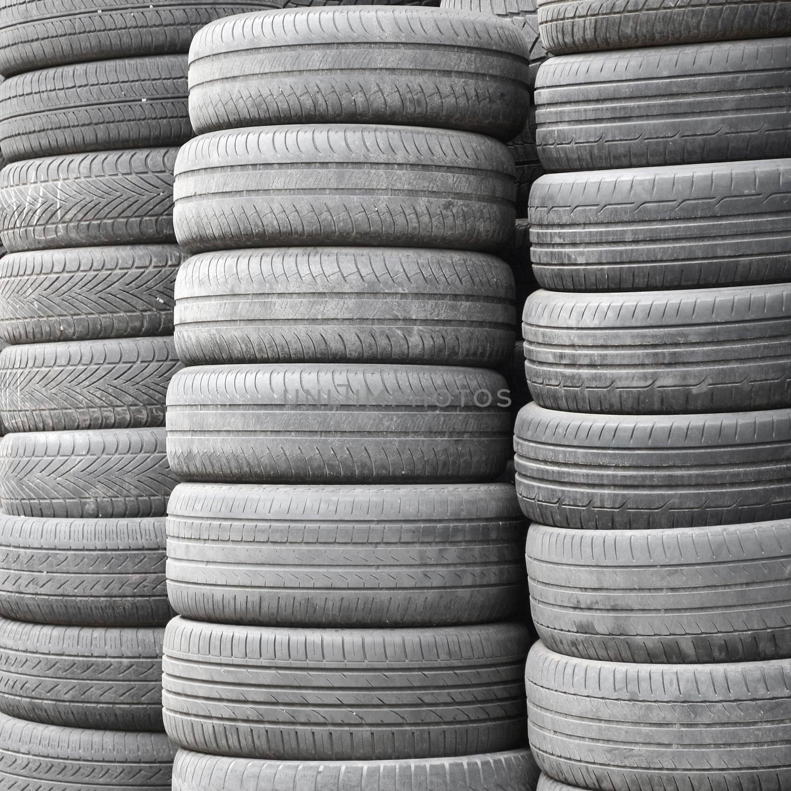 Old used tires stacked with high piles in secondary car parts shop garage close up