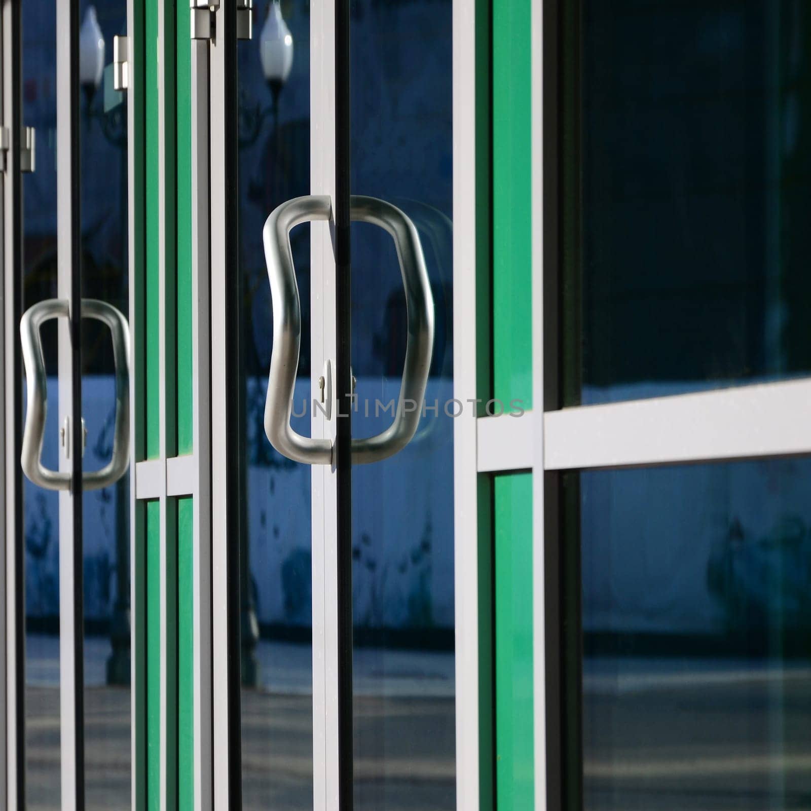 Chrome door handle and glass of modern aluminium door outside the office building