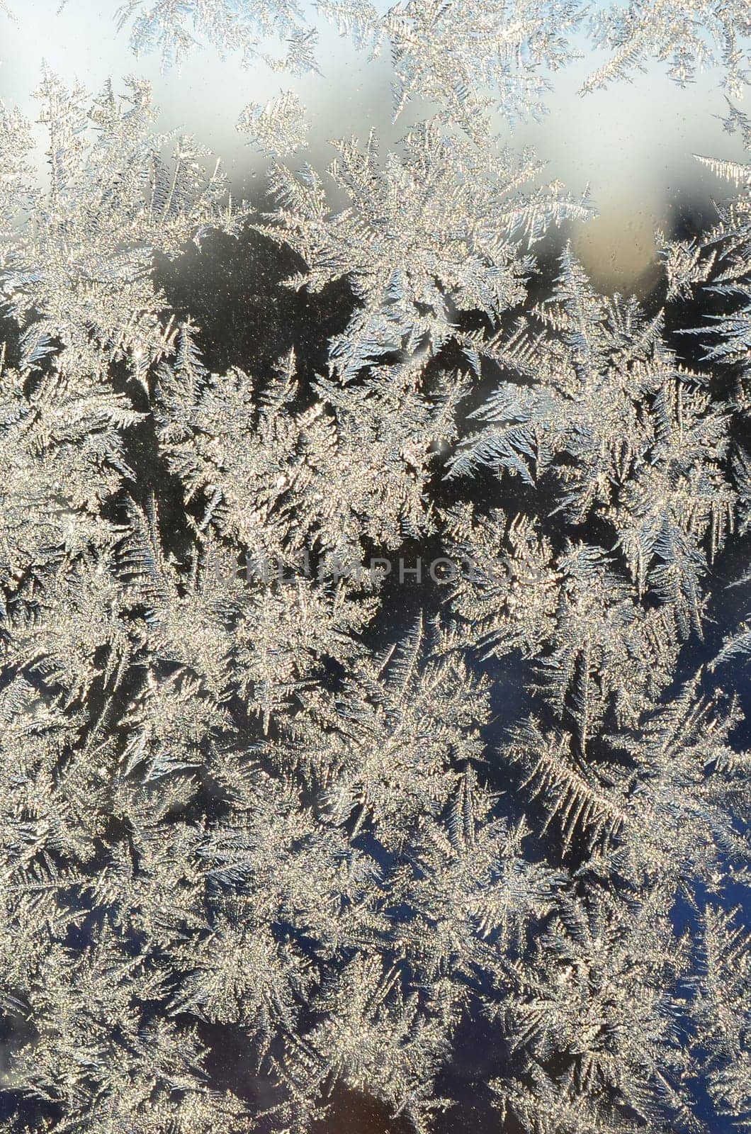 Snowflakes frost rime macro on window glass pane. Colorful ice on the window surface, natural background texture