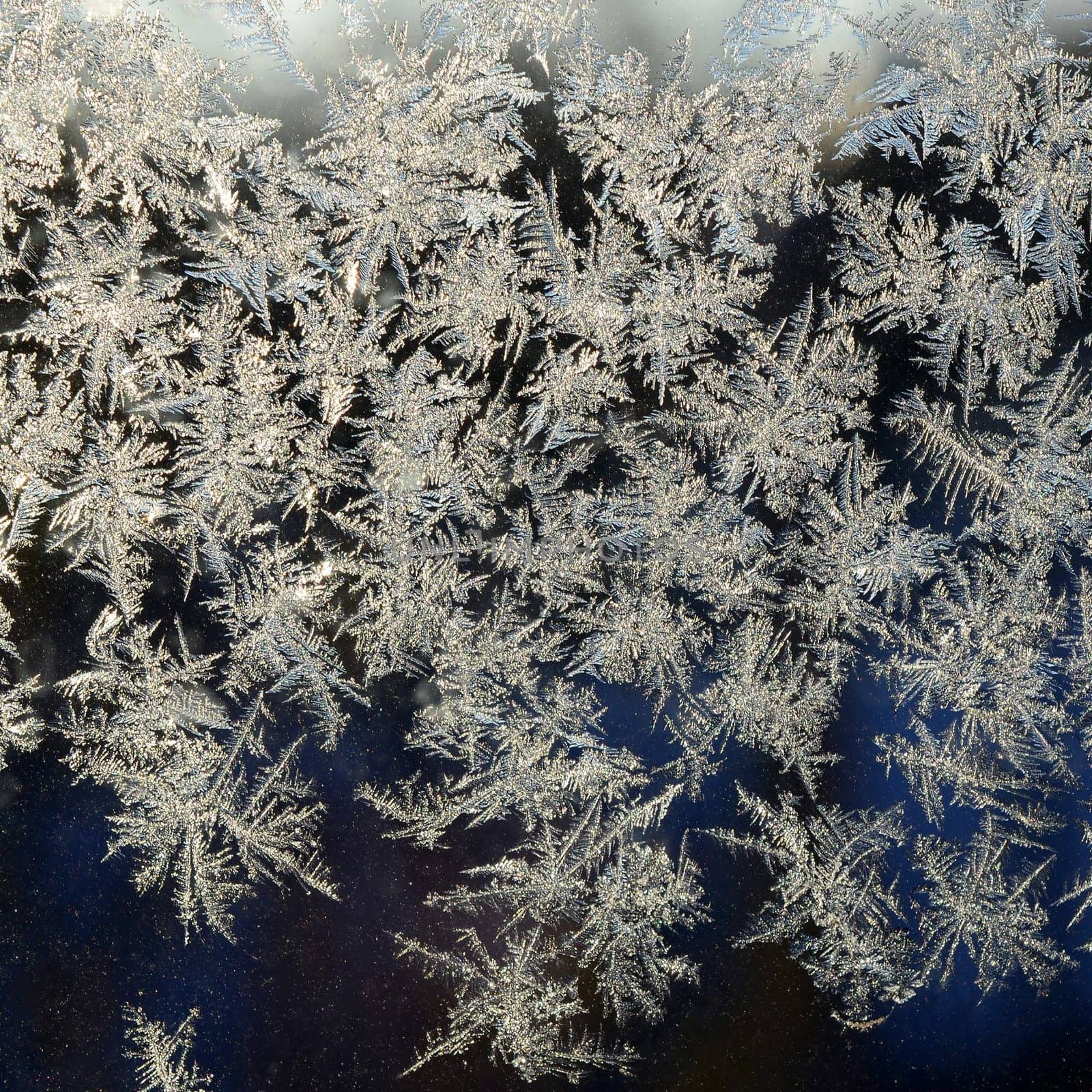 Snowflakes frost rime macro on window glass pane. Colorful ice on the window surface, natural background texture